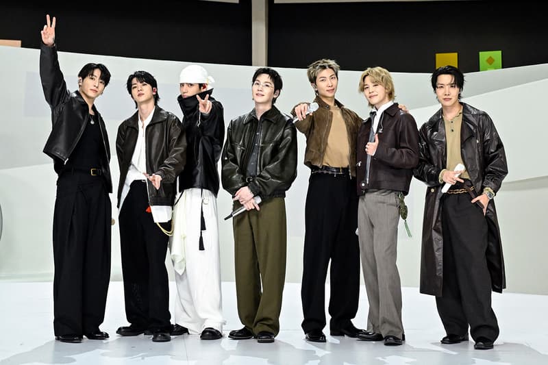 Sept hommes posant en vêtements élégants sur fond neutre.