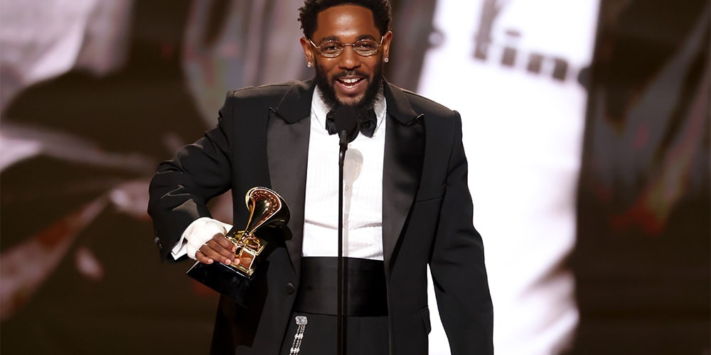 Homme en smoking tenant un trophée sur scène.