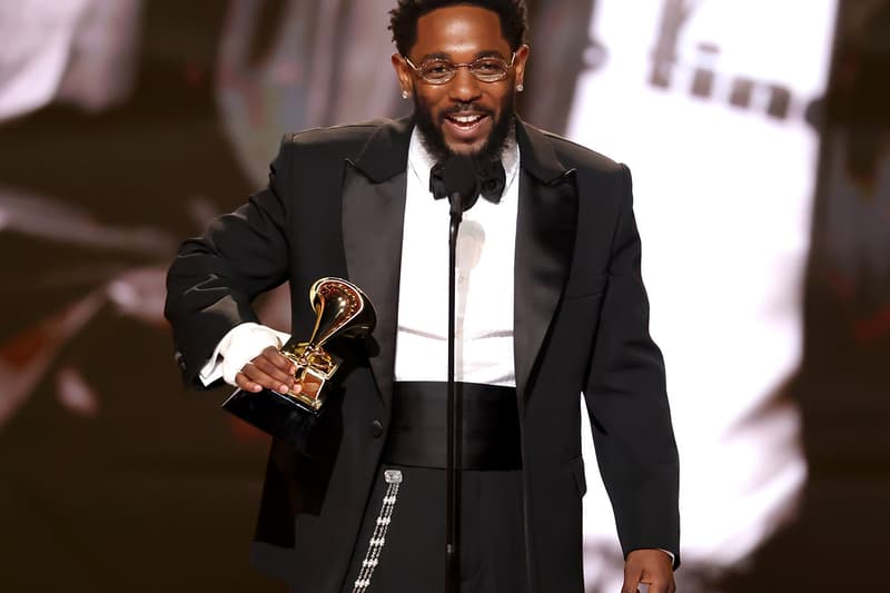 Homme en costume tient un trophée sur scène, souriant au public