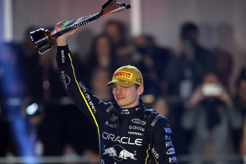 Coureur automobile avec trophée et casquette de vainqueur.