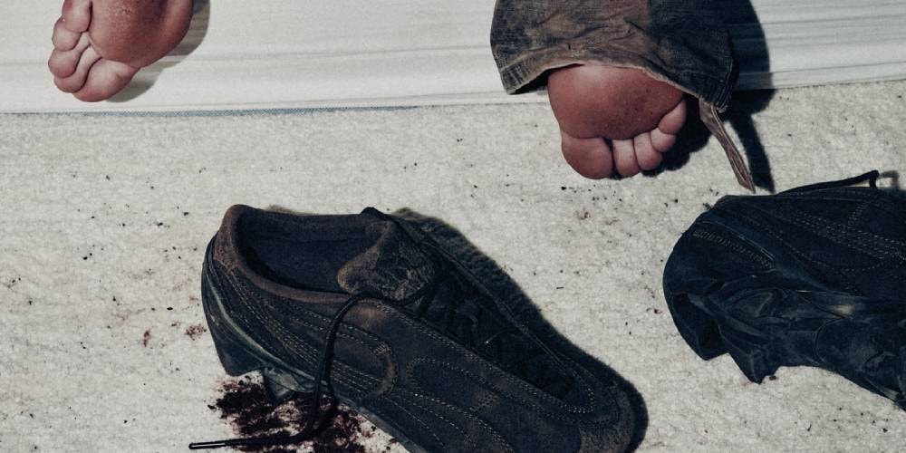 Personnes allongées, pieds nus visibles, chaussures sur le sol, sur fond de tapis blanc.